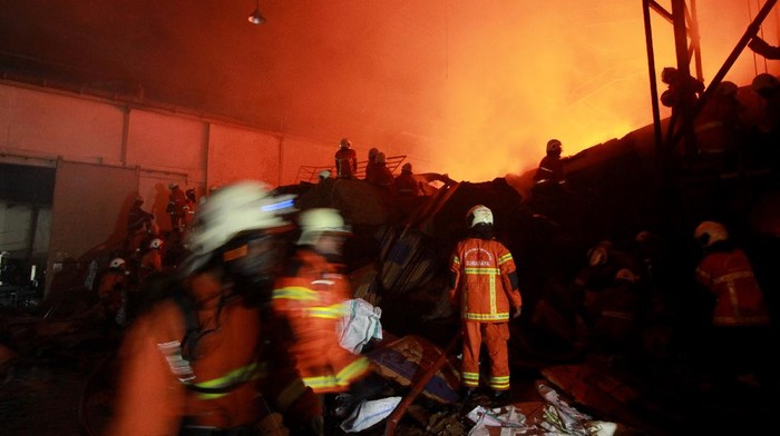Petugas Dinas Pemadam Kebakaran Kota Surabaya memadamkan api yang membakar sebuah pabrik di Jalan Tambak Osowilangun, Surabaya, Jawa Timur, Senin (5/4/2021) dini hari. Sebanyak 18 kendaraan pemadam kebakaran dikerahkan untuk memadamkan kebakaran pabrik yang memproduksi barang-barang dari plastik itu. ANTARA FOTO/Didik Suhartono/aww.