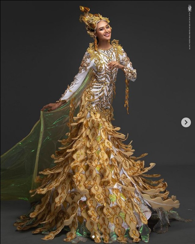 Dalam ajang Miss Grand International 2020 ketika penjurian kostum nasional, Han Lay mengenakan busana bertajuk A Goddess of Peace. Kostum yang didominasi warna kuning keemasan dan putih itu melambangkan kedamaian yang dibutuhkan oleh dunia. Kostum itu dibuat dengan refleksi dari Dewi Perdamaian yang memercikkan air mata cinta dengan tangkai Aung Tha Pyae (Eugenia) dan melambangkan kemenangan perdamaian dengan ornamen Myanmar. Foto: Dok. Instagram @hann_may, Facebook Miss Grand International