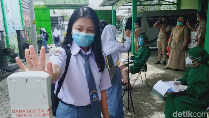 Salah seorang siswa SMAN 3 Klaten mengecek suhu tubuhnya sebelum mengikuti sekolah tatap muka, Senin (5/4/2021)
