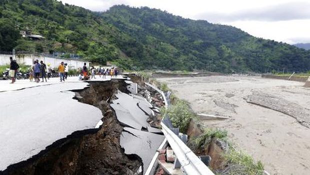 Residents inspect a damaged road following a flood in Dili, East Timor, Monday, April 5, 2021. Multiple disasters caused by torrential rains in eastern Indonesia and neighboring East Timor have left a number of people dead or missing as rescuers were hampered by damaged bridges and roads and a lack of heavy equipment Monday. (AP Photo/Kandhi Barnez)