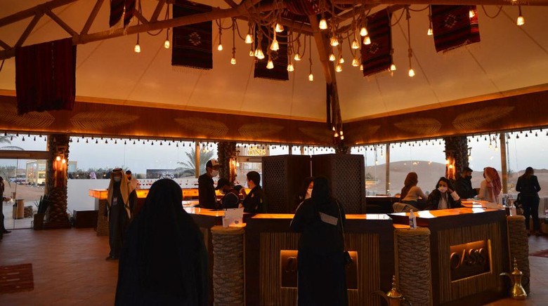 Visitors relax in a lounge area beneath palm trees at the 