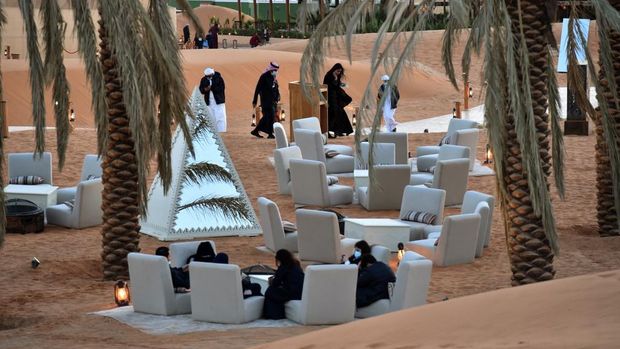 Visitors relax in a lounge area beneath palm trees at the 