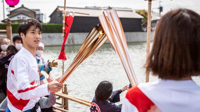 HANDA, JAPAN - APRIL 06: A torch bearer holds the torch on the boat called ‘Chintoro boat’, used in a local festival dating back to the Edo Period during the Tokyo Olympic Games Torch Relay on April 06, 2021 in Handa, Aichi, Japan. (Photo by Yuichi Yamazaki/Getty Images)