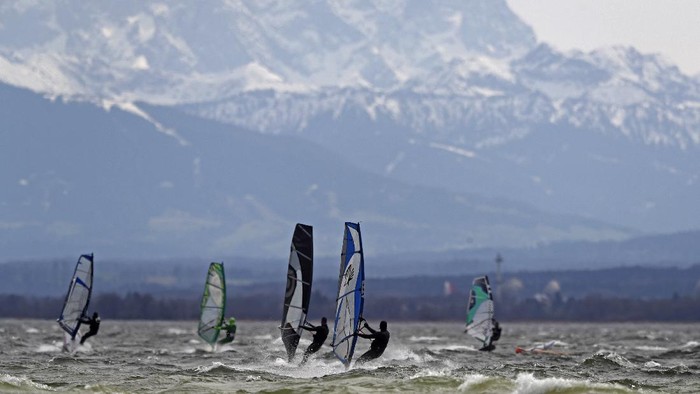 Surfers brave high winds to speed on the waves at lake Ammersee in front of the Alps near Herrsching, Germany, Monday, April 5, 2021. (AP Photo/Matthias Schrader)