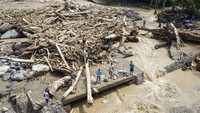 Tampak sisa-sisa kayu yang terbawa arus banjir menumpuk di tengah sungai.