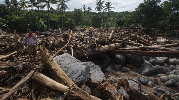 Warga melewati tumpukan kayu-kayu yang menyumbat dan merusak salah satu jembatan penghubung antardesa di Adonara Timur, Kabupaten Flores Timur, Nusa Tenggara Timur (NTT), Rabu (7/4/2021). Menurut Organisasi Wahana Lingkungan Hidup Indonesia (Walhi), banjir bandang dan tanah longsor yang melanda di sejumlah wilayah di NTT dipicu kerusakan lingkungan akibat alih fungsi lahan, pertambangan, dan pembalakan liar. ANTARA FOTO/Aditya Pradana Putra/hp.