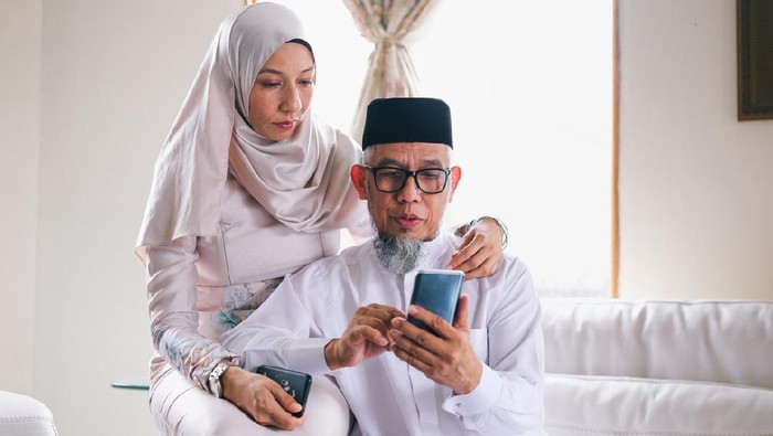 Father and daughter looking at phone during raya celebration in Malaysia
