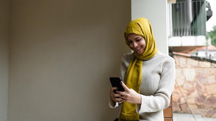 Young woman, cloth on her head, on the phone, working, looking at Ramadan, religious dress