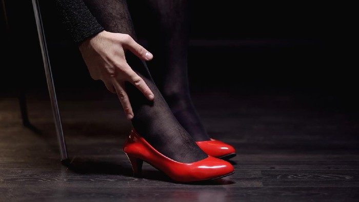 Ilustrasi Transgender Transgender man in female shoes and pantyhose stroking leg, admiring femininity