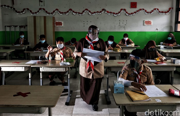 Guru memberikan pelajaran kepada murid saat uji coba belajar tatap muka di kawasan SDN 11 Pademangan Barat, Jakarta Utara, Rabu (7/4). SDN Pademangan Barat 11 memulai uji coba belajar tatap muka bagi siswa kelas V di tengah pandem COVID-19. Protokol kesehatan menjadi hal utama baik bagi siswa maupun tenaga pendidik.