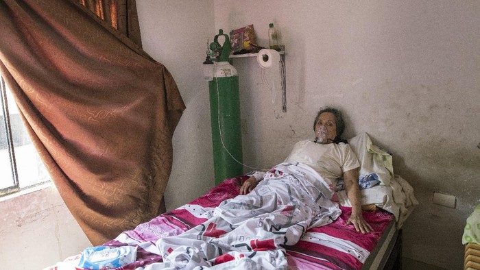 A man sleeps on top of empty oxygen cylinders that stretch across a dirt road, as people wait for a shop to open in order to refill their tanks, in the Villa El Salvador neighborhood, as the lack of medical oxygen to treat COVID-19 patients continues in Lima, Peru, Tuesday, April 6, 2021. (AP Photo/Rodrigo Abd)