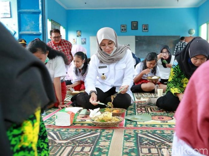 Senyum bahagia terpancar dari para pelajar SD Negeri 2 dan SMPN 3 di Desa Kajarharjo, Kecamatan Kalibaru, saat bertemu dan sarapan bareng Bupati Banyuwangi Ipuk Fiestiandani. Mereka menikmati makan bersama dengan bupati perempuan tersebut. Menu yang disajikan adalah nasi pecel dengan lauk ikan laut, tempe dan telur bumbu bali.