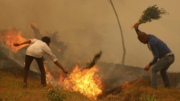 In this picture taken on March 5, 2021, residents battle a fire in a forest in Baglung, about 275 km west of Kathmandu. (Photo by Riwaj SHARMA / AFP)