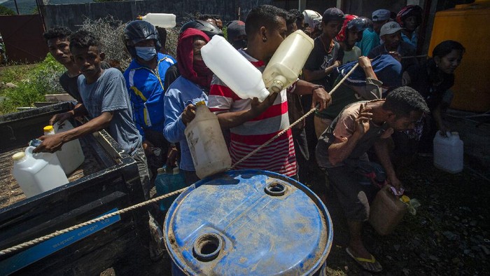 Warga Korban Banjir NTT Antre BBM Polisi mengatur sejumlah warga bergiliran membeli bahan bakar minyak (BBM) minyak tanah dan pertalite di lokasi distribusi darurat di Waiwerang, Adonara Timur, Kabupaten Flores Timur, Nusa Tenggara Timur, Rabu (7/4/2021). Pertamina melaksanakan distribusi BBM di lokasi darurat dengan dijaga aparat karena Stasiun Pengisian Bahan Bakar Umum (SPBU) dan pangkalan resmi minyak tanah belum bisa beroperasi karena terdampak lumpur akibat banjir bandang. ANTARA FOTO/Aditya Pradana Putra/foc.