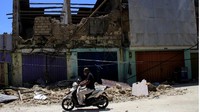 Seorang pengendara bermotor melintas di depan salah satu gedung yang ambruk akibat badai Siklon tropis Seroja di Kota Kupang, NTT.