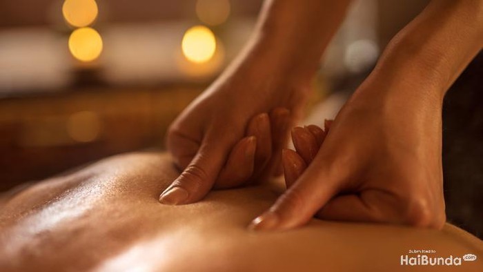 Close-up of massage therapist applying pressure on mans back at the spa.