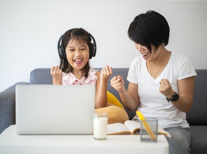 Asian girl and her teacher using laptop for online study during homeschooling at home during Coronavirus or Covid-19 virus outbreak situation