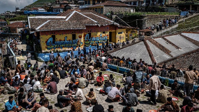 MAGELANG, INDONESIA - APRIL 09:  Javanese muslims eat together after praying at a cemetery during a Nyadran ritual in Butuh village at the foot of Mount Sumbing on April 9, 2021 in Magelang, Central Java, Indonesia. Before the month of Ramadan begins, Javanese Muslims takes part in a unique ritual called Nyadran, which originated as a way to share Islamic beliefs with local villagers, many of who were not Muslim. For Nyadran, people visit the graves of their ancestors to pay respect, but the event is also an expression of friendship between villagers who live at the foot of mountains in central Java. After praying they eat together and they will celebrate by visiting their neighbor's houses. (Photo by Ulet Ifansasti/Getty Images)