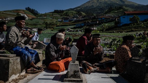 MAGELANG, INDONESIA - APRIL 09:  Javanese muslims pray at the cemetery during a Nyadran ritual in Butuh village at the foot of Mount Sumbing on April 9, 2021 in Magelang, Central Java, Indonesia. Before the month of Ramadan begins, Javanese Muslims takes part in a unique ritual called Nyadran, which originated as a way to share Islamic beliefs with local villagers, many of who were not Muslim. For Nyadran, people visit the graves of their ancestors to pay respect, but the event is also an expression of friendship between villagers who live at the foot of mountains in central Java. After praying they eat together and they will celebrate by visiting their neighbors houses. (Photo by Ulet Ifansasti/Getty Images)