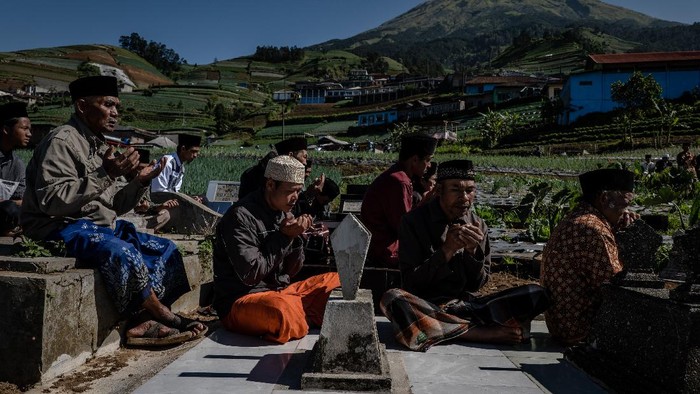 MAGELANG, INDONESIA - APRIL 09:  Javanese muslims pray at the cemetery during a Nyadran ritual in Butuh village at the foot of Mount Sumbing on April 9, 2021 in Magelang, Central Java, Indonesia. Before the month of Ramadan begins, Javanese Muslims takes part in a unique ritual called Nyadran, which originated as a way to share Islamic beliefs with local villagers, many of who were not Muslim. For Nyadran, people visit the graves of their ancestors to pay respect, but the event is also an expression of friendship between villagers who live at the foot of mountains in central Java. After praying they eat together and they will celebrate by visiting their neighbors houses. (Photo by Ulet Ifansasti/Getty Images)