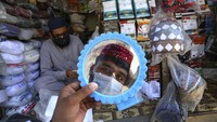 Seorang pria mencoba topi tradisional untuk persiapan bulan  puasa Ramadhan, di Peshawar, Pakistan. AP Photo/Muhammad Sajjad  