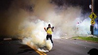 Ratusan orang yang marah menggelar aksi protes di luar gedung Departemen Kepolisian Brooklyn Center di Minneapolis pada Minggu (11/4) malam waktu setempat. Polisi yang mengenakan perlengkapan antihuru-hara menembakkan peluru karet dan melemparkan granat cahaya ke arah demonstran. AP/Jeff Wheeler  