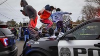 Beberapa demonstran bahkan melakukan vandalisme terhadap dua mobil polisi yang ada di lokasi. Mereka melemparkan batu dan menginjak-injak mobil polisi tersebut. AP/Christian Monterrosa  