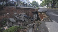 Warga memfoto jalan yang longsor di Jalan Raya Boulevard, GDC, Depok, Jawa Barat, Selasa (13/4/2021).