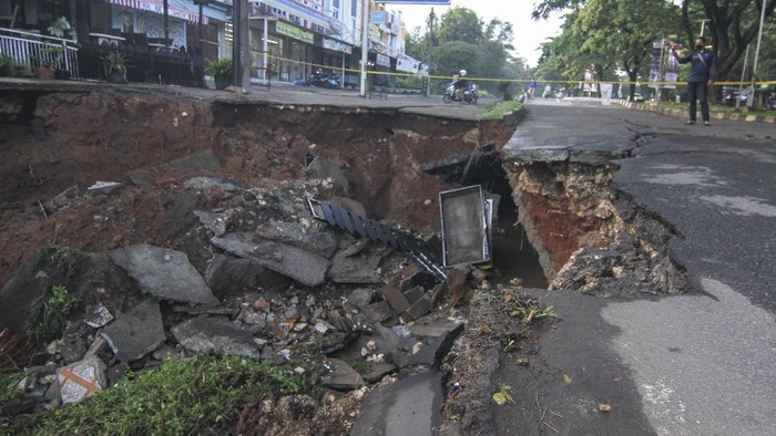 Sejumlah warga melihat jalan yang longsor di Jalan Raya Boulevard, GDC, Depok, Jawa Barat, Selasa (13/4/2021). Longsor yang terjadi pada Senin (12/4) pukul 21.00 WIB tersebut akibat intensitas hujan yang tinggi  dan menyebabkan sebagain jalan amblas dengan kedalaman dan lebar kurang lebih 5 meter. ANTARA FOTO/Asprilla Dwi Adha/hp.