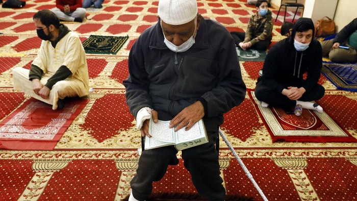 A Muslim makes a donation after an evening prayer called 