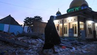 Seorang warga berjalan melintasi puing reruntuhan sebuah rumah akibat gempa untuk menuju mushala Al Mutaqin, Majangtengah, Malang, Jawa Timur, dan melaksanakan salat tarawih, Senin (12/4/2021). ANTARA FOTO/Ari Bowo Sucipto.