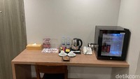 Dimulai dari atas meja yang bisa digunakan untuk makan dan kerja ada nampan yang dilengkapi pemanas air, dua cangkir kopi, kopi dan teh sachet. Di situ juga ada mini bar.