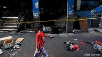 Warga melintas di depan pasar yang terbakar.