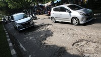 Sejumlah pengendara melintasi jalan yang rusak.