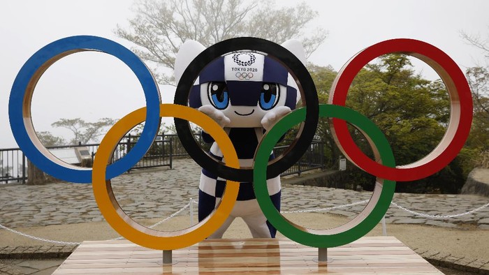 Tokyo 2020 Olympic Games mascot Miraitowa poses with a display of Olympic Symbol after an unveiling ceremony of the symbol on Mt. Takao in Hachioji, west of Tokyo, Wednesday, April 14, 2021, to mark 100 days before the start of the Olympic Games. (Kim Kyung-Hoon/Pool)