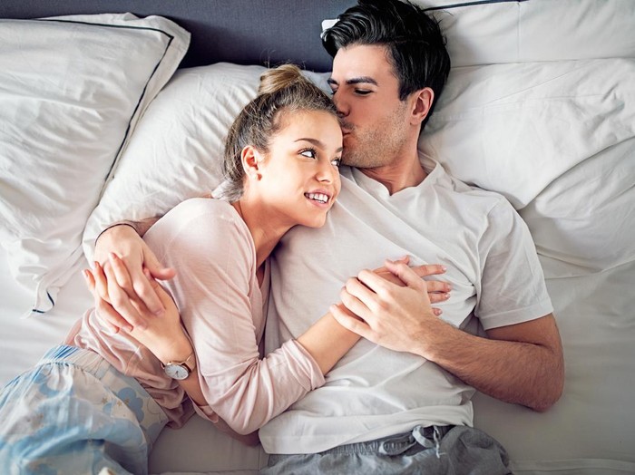 Couple is kissing and hugging in bed