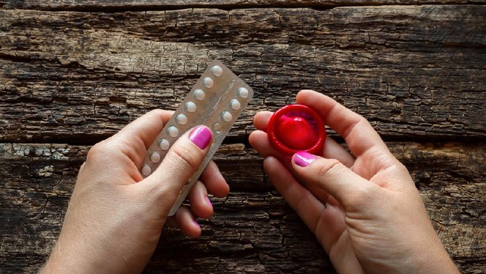 kontrasepsi young woman holding a birth control pills and a condom