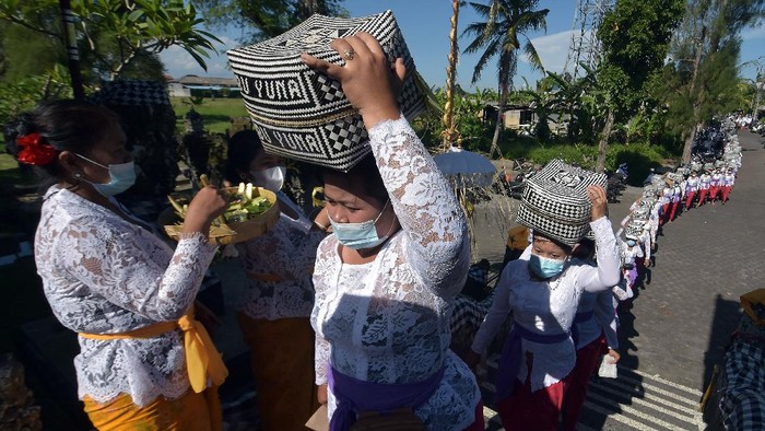 Umat Hindu mengusung keben bambu atau tempat sesajen dalam tradisi Mapeed yaitu rangkaian persembahyangan Hari Raya Galungan di Desa Lukluk, Badung, Bali, Rabu (14/4/2021). Tradisi yang biasanya berjalan beriringan dengan menjunjung gebogan atau sesajen bersusun buah, bunga dan hiasan janur tersebut digelar secara sederhana untuk menekan pengeluaran bagi warga di masa pandemi COVID-19. ANTARA FOTO/Nyoman Hendra Wibowo/hp.