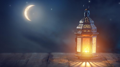 Ornamental Arabic lantern with burning candle glowing at night. Festive greeting card, invitation for Muslim holy month Ramadan Kareem.