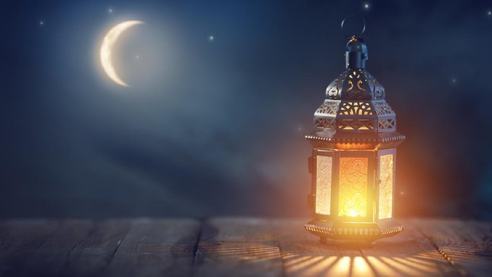 Ornamental Arabic lantern with burning candle glowing at night. Festive greeting card, invitation for Muslim holy month Ramadan Kareem.n