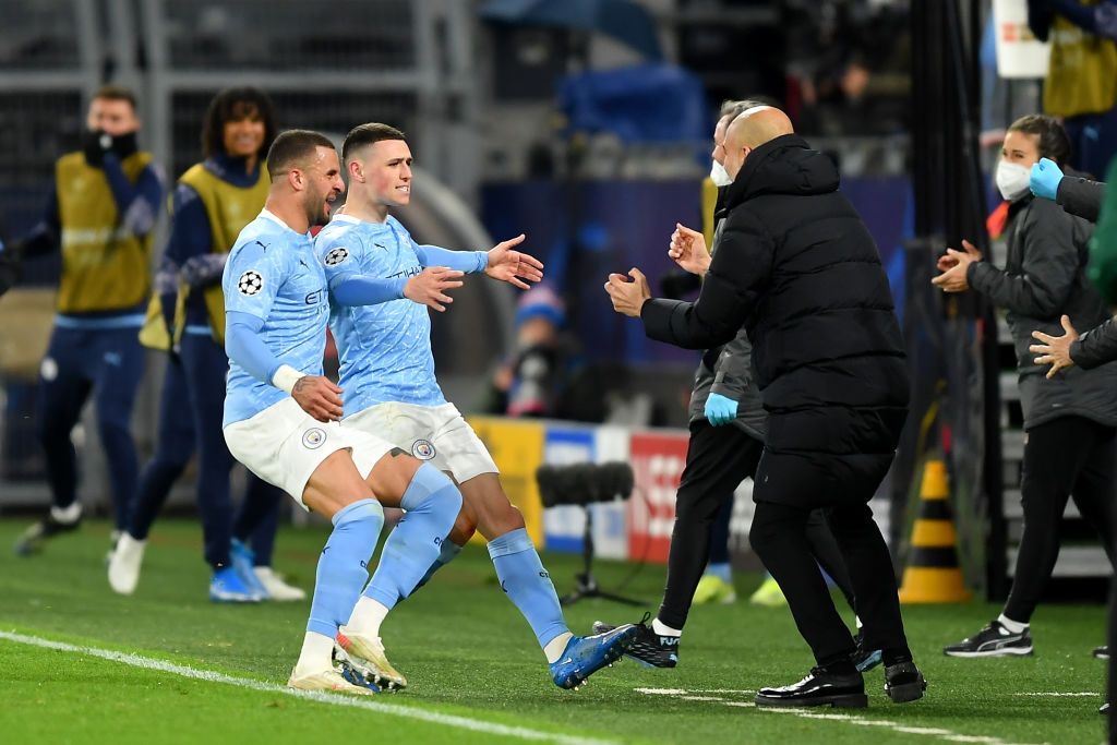 DORTMUND, GERMANY - APRIL 14: Phil Foden of Manchester City runs towards Pep Guardiola, Manager of Manchester City as he celebrates with team mate Kyle Walker after scoring their side's second goal during the UEFA Champions League Quarter Final Second Leg match between Borussia Dortmund and Manchester City at Signal Iduna Park on April 14, 2021 in Dortmund, Germany. Sporting stadiums around Germany remain under strict restrictions due to the Coronavirus Pandemic as Government social distancing laws prohibit fans inside venues resulting in games being played behind closed doors.  (Photo by Friedemann Vogel - Pool/Getty Images)