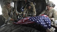 Seorang paramedis Angkatan Udara yang mengibarkan bendera Amerika di atas sisa-sisa dua tentara AS yang terbunuh oleh alat peledak rakitan.  