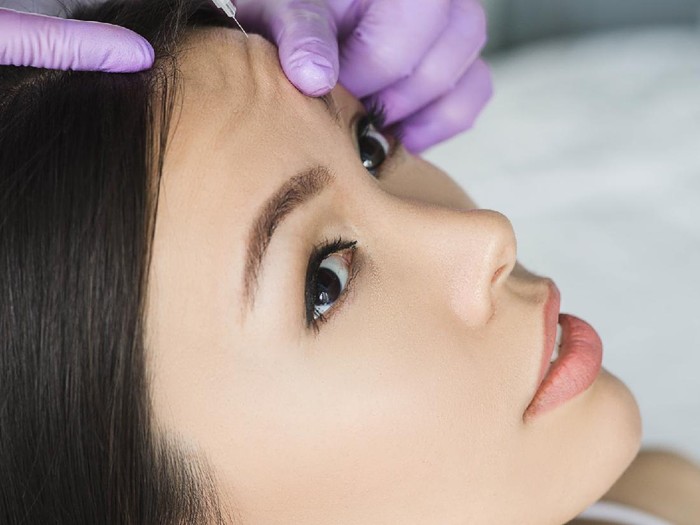 1173337122 asian woman receiving injection into mimic wrinkle on forehead . Procedure removing wrinkle