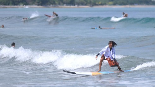 Peselancar wanita yang mengenakan busana kebaya berselancar di Pantai Kuta, Badung, Bali, Jumat (16/4/2021). Kegiatan yang diikuti puluhan perempuan termasuk sejumlah WNA tersebut dilakukan untuk menyambut peringatan Hari Kartini serta membangkitkan sektor pariwisata Bali yang terdampak pandemi COVID-19. ANTARA FOTO/Fikri Yusuf/wsj.