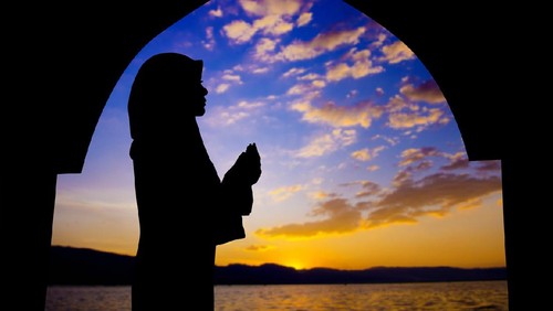 Arab woman with veil against orange yellow sky