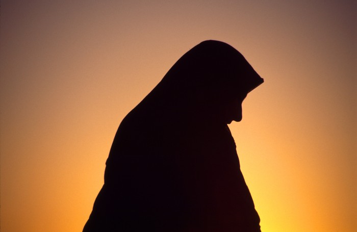 Ilustrasi wanita muslim Arab woman with veil against orange yellow sky