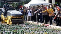 Alat berat bergerak untuk menggilas botol miras.