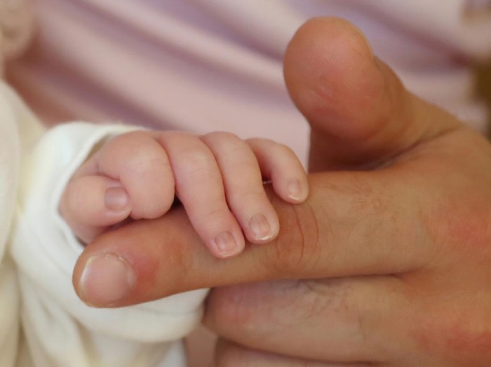 A newborn baby holding his fathers hand