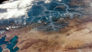 Astronaut di ISS mengabadikan ngarai di Pegunungan Andes di Bolivia yang diselimuti asap. Asap ini berasal dari kebakaran di hutan Yungas yang terlihat berwarna hijau dan diselimuti awan. Foto: NASA