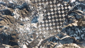 Kawasan yang terlihat seperti papan catur raksasa ini berada di dekat Sungai Priest di bagian utara Idaho, Amerika Serikat. Pola papan catur ini merupakan hasil dari manajemen hutan untuk melindungi pohon yang masih muda tapi tetap memungkinkan penebangan pohon. Foto: NASA